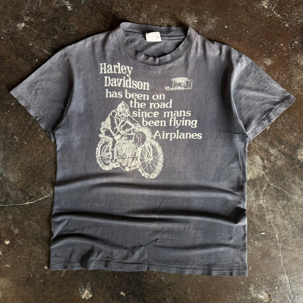 Black short-sleeve t-shirt with airplane graphic and Since Airplanes text, sun faded condition