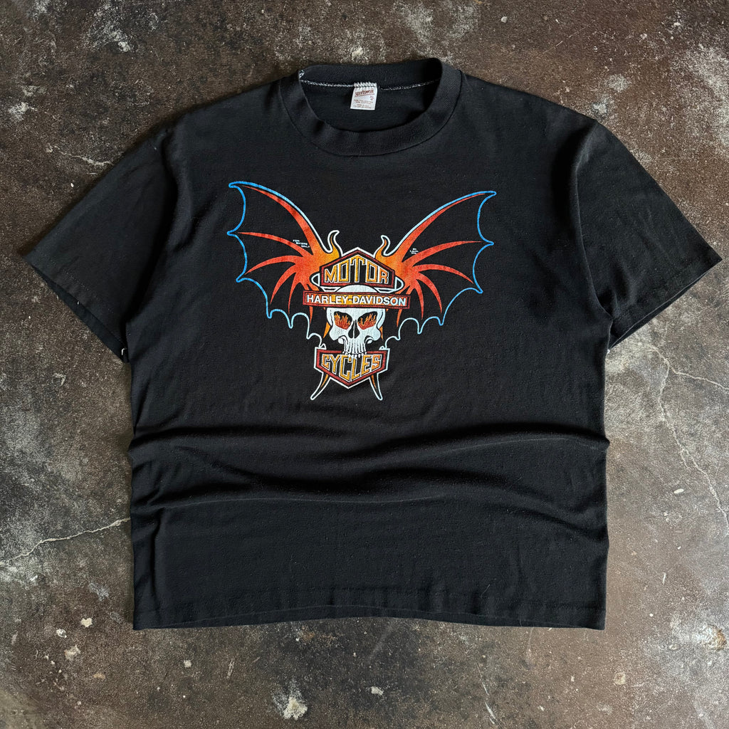 Black short-sleeve t-shirt with centered orange and red bat-winged skull graphic on chest