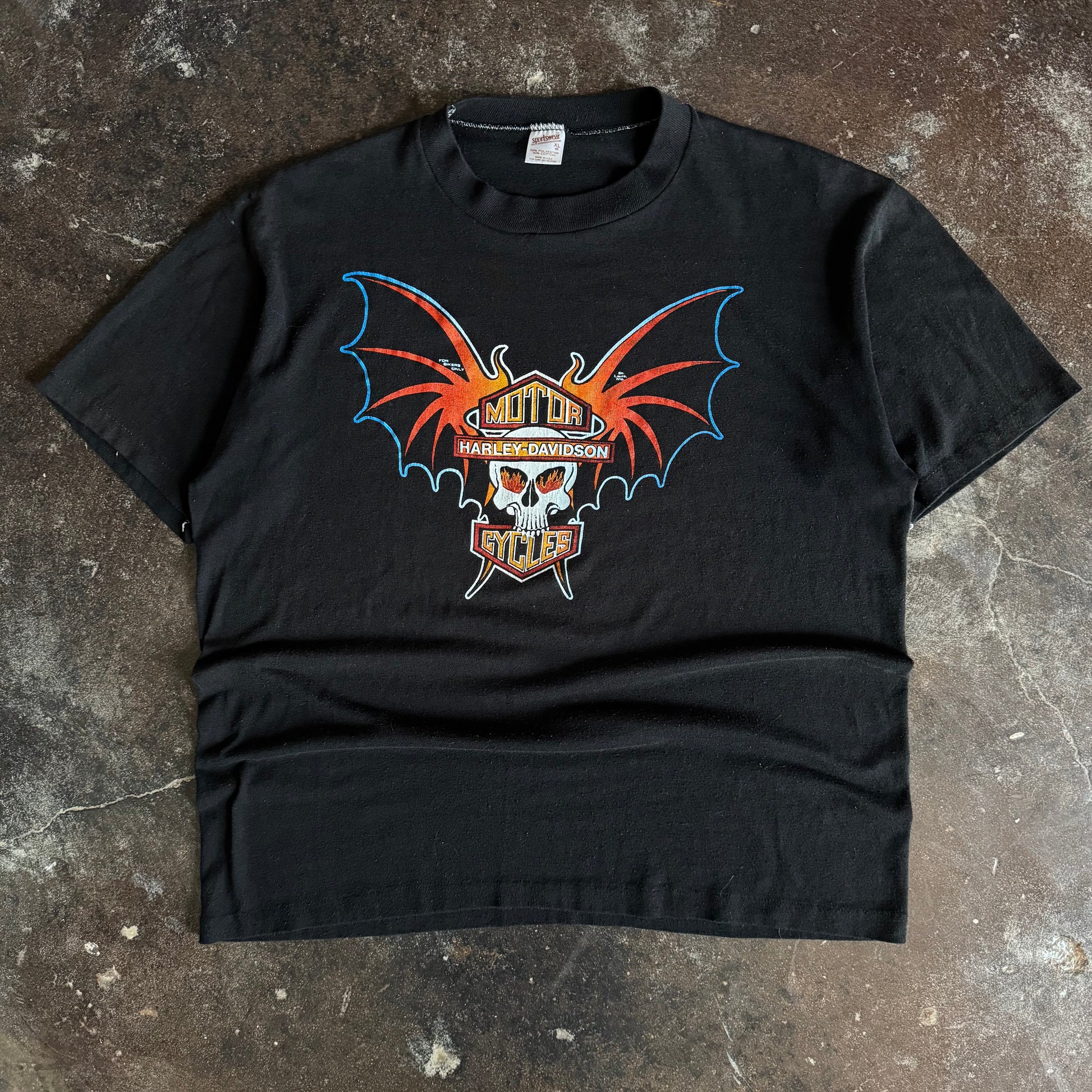 Black short-sleeve t-shirt with centered orange and red bat-winged skull graphic on chest