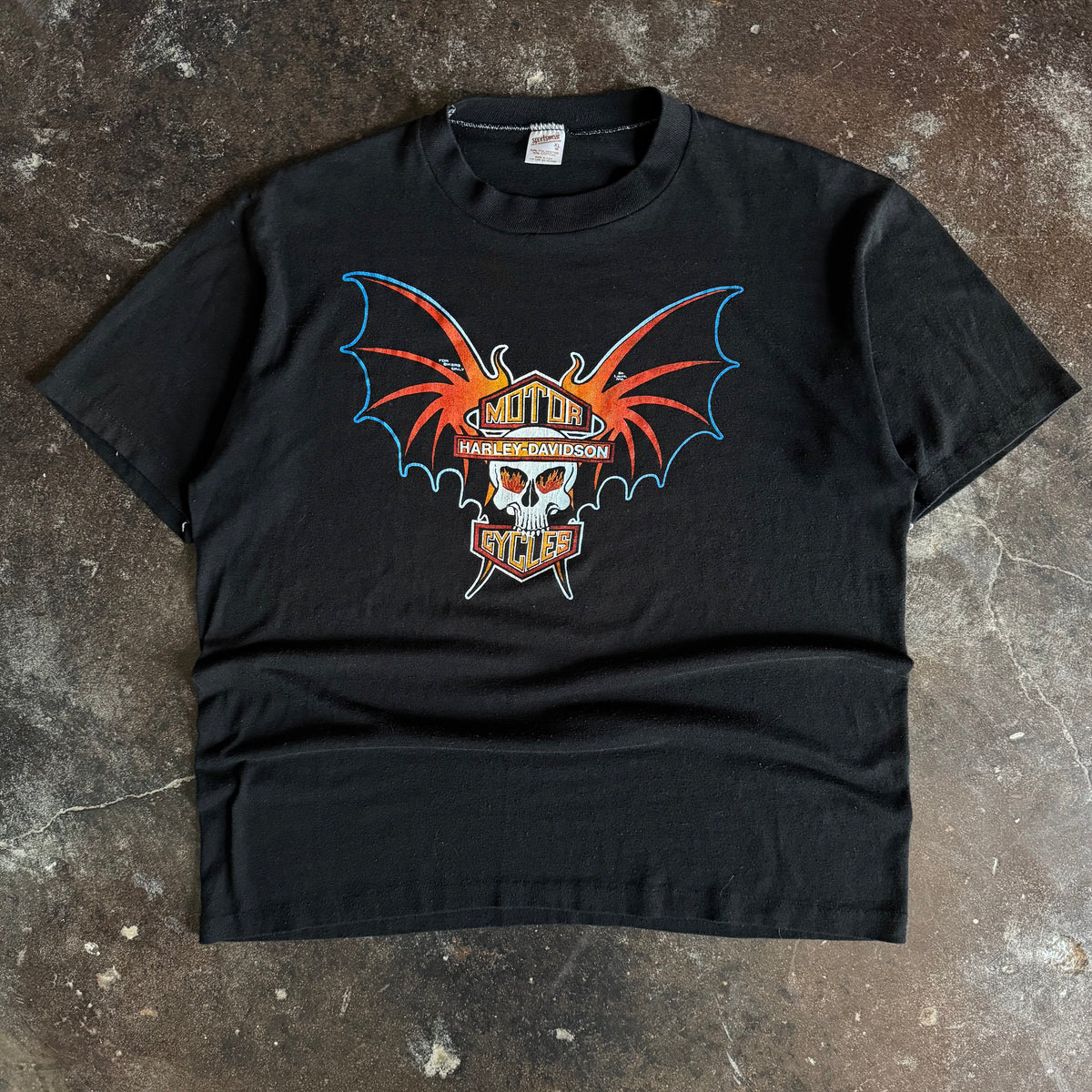 Black short-sleeve t-shirt with centered orange and red bat-winged skull graphic on chest