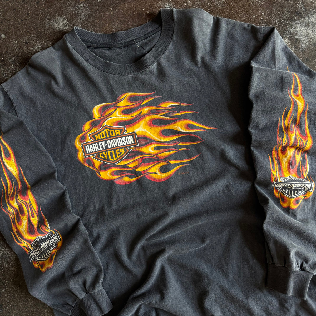 Detail of rushing flames bar and shield graphic on vintage sun faded Harley longsleeve